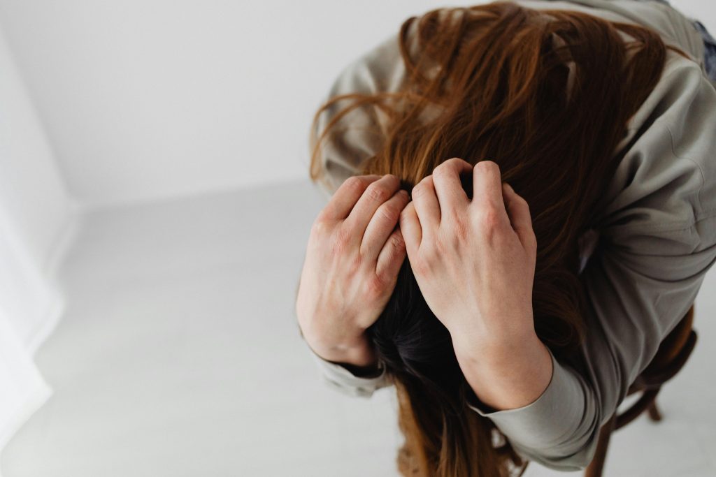 Stressed woman holding strands of hair, representing hormonal hair loss and emerging peptide therapy for androgenetic alopecia.