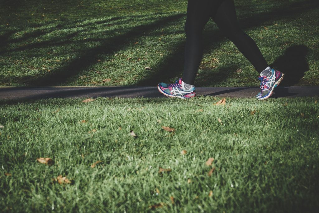 Athletic shoes walking through grass, symbolizing daily walking for better health and longevity.