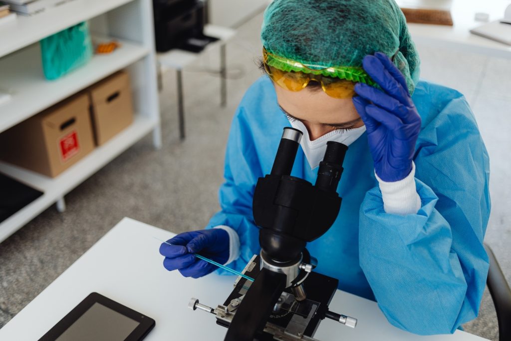 Scientist examining human cells under a microscope to study cellular senescence and aging.